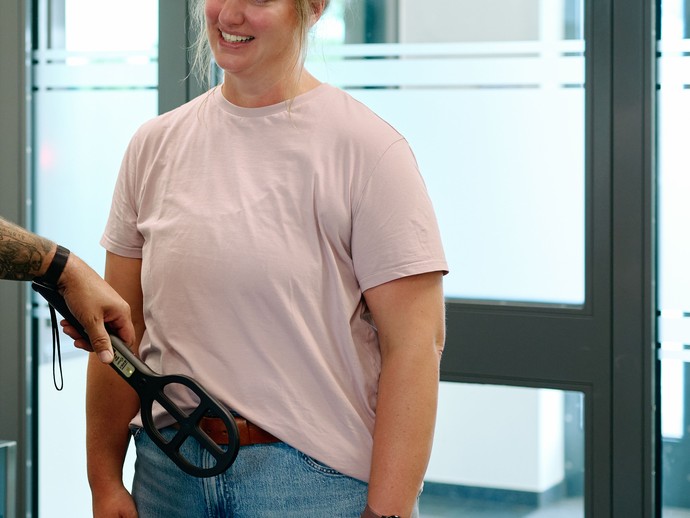 Eine Frau wird mit einem Handdetektor durchsucht