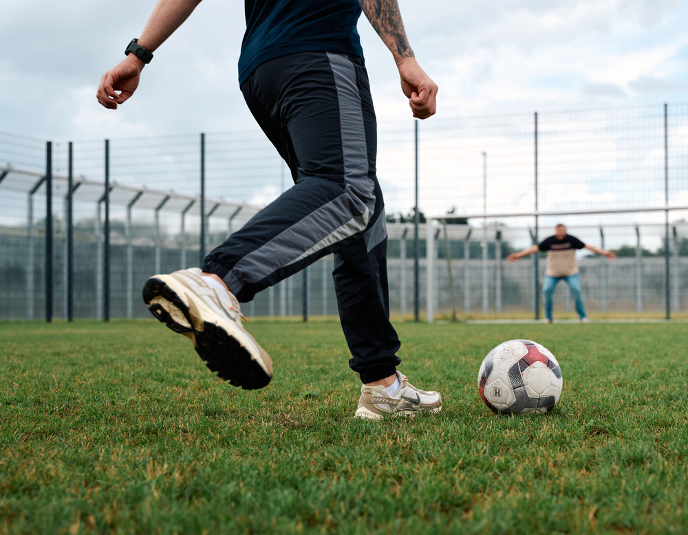 Eine Person schießt einen Ball in Richtung eines Tores, in dem eine andere Person steht.