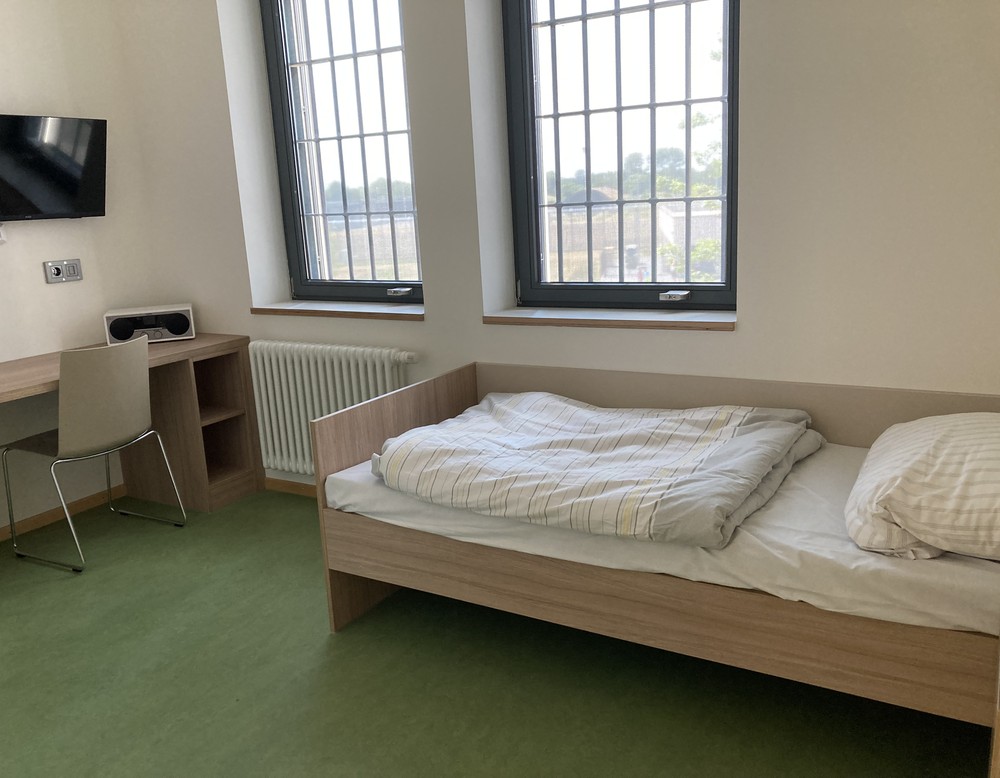 Ein heller Flur einer geschlossenen Therapiestation mit mehreren geschlossenen gelben Türen und mehreren gemütlichen Korbstühlen.